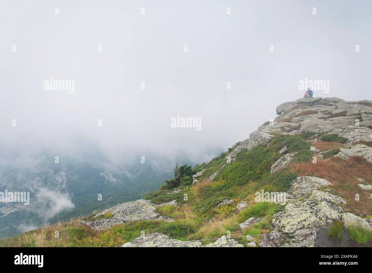 Une personne méconnaissable assise sur un rocher au sommet du mont mansfield dans underhill vermont. Banque D'Images