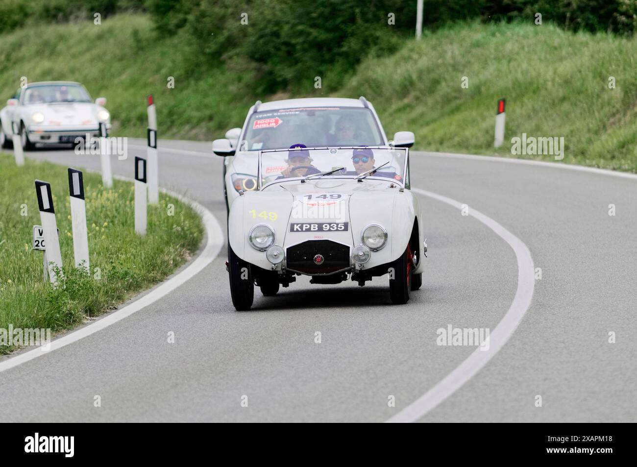 Voiture de course blanche classique conduisant sur une route de campagne sinueuse à travers des champs verts sur une journée ensoleillée, voiture classique, course de voiture, mille Miglia, 1000 Miglia Banque D'Images