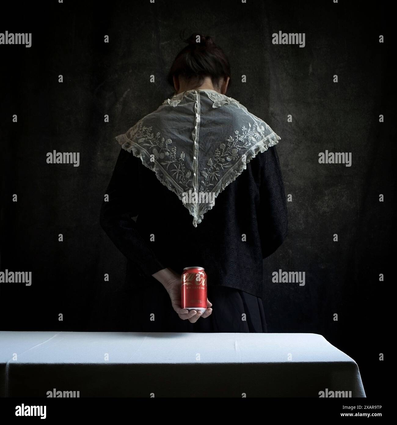 Femme au style édouardien et collier en dentelle dans une scène domestique derrière une table avec une nappe en lin blanc, une scène qui réinterprète le style de th Banque D'Images