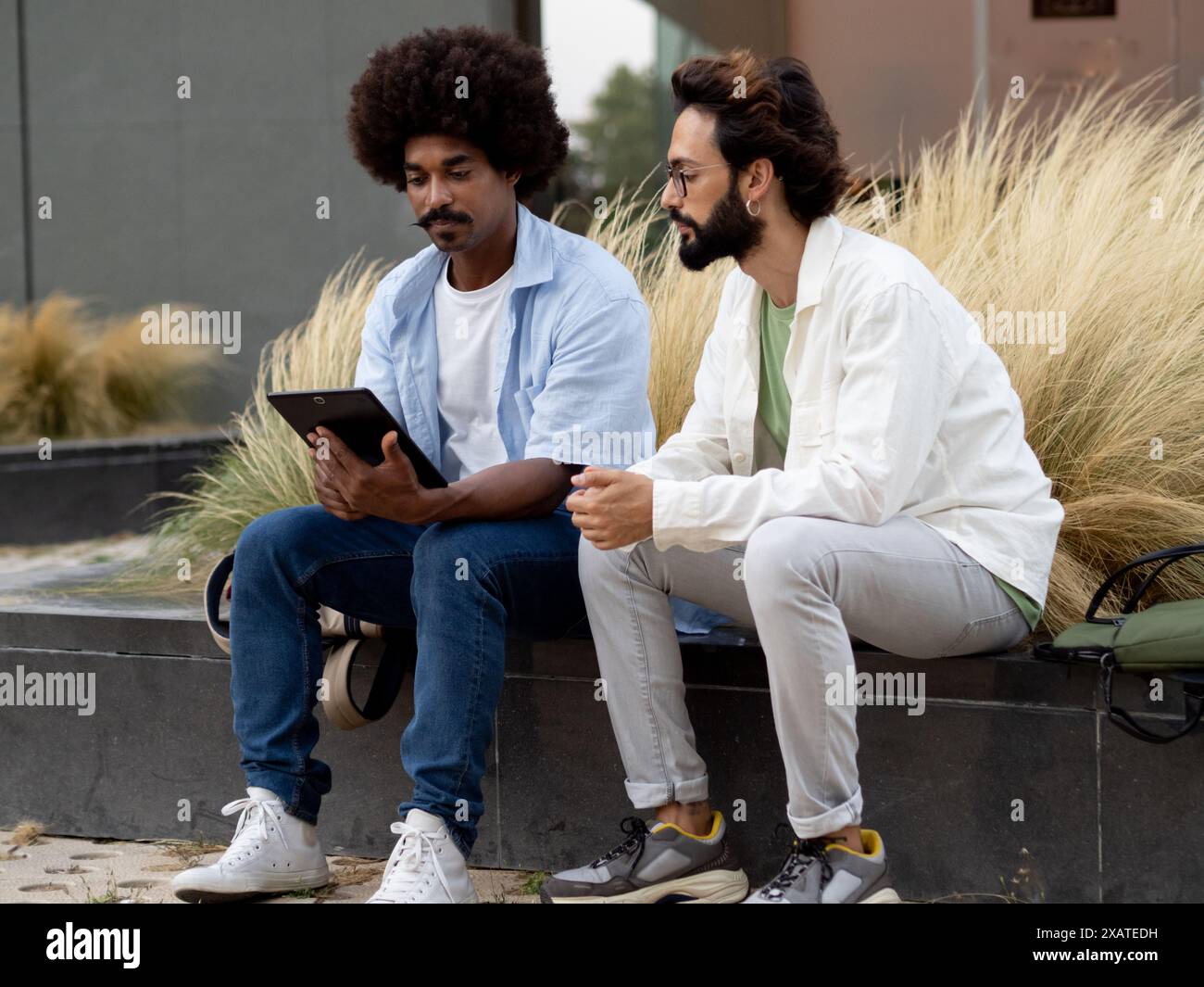 Deux jeunes indépendants masculins divers travaillant ensemble dans un quartier financier avec une tablette Banque D'Images