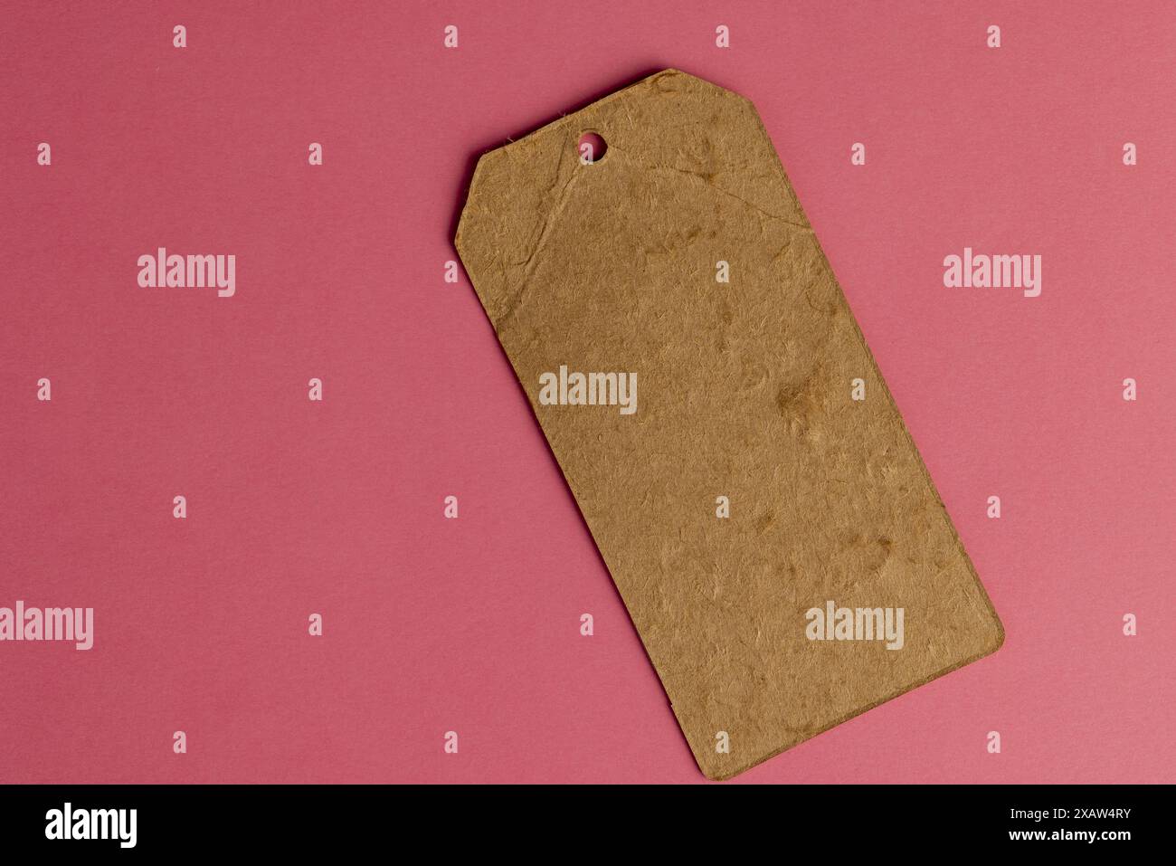 ancienne étiquette de vêtements en carton fabriquée à partir de vieux papiers recyclés étiquette d'article écologique sur fond rose Banque D'Images