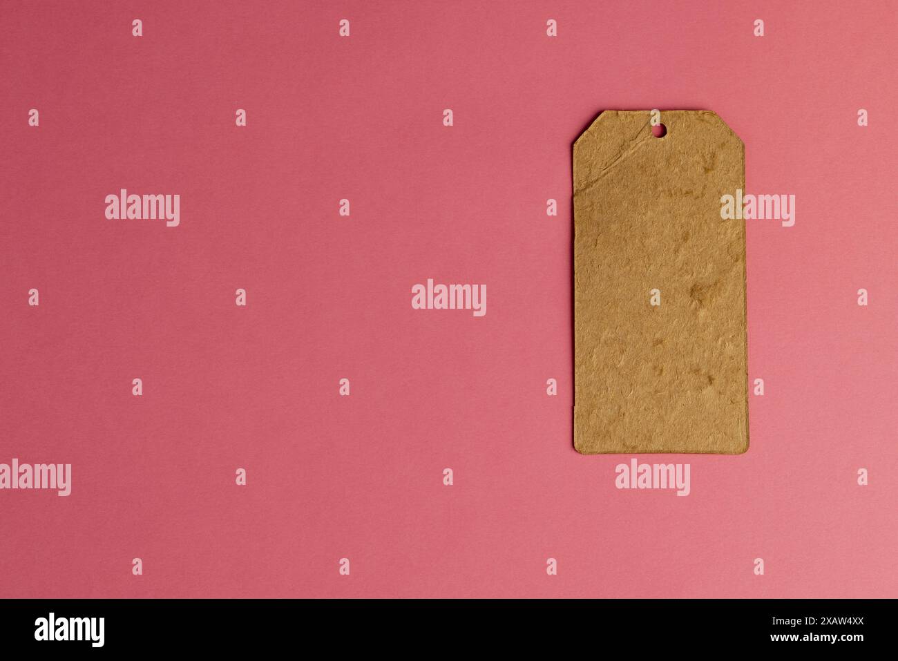 ancienne étiquette de vêtements en carton fabriquée à partir de vieux papiers recyclés étiquette d'article écologique sur fond rose Banque D'Images