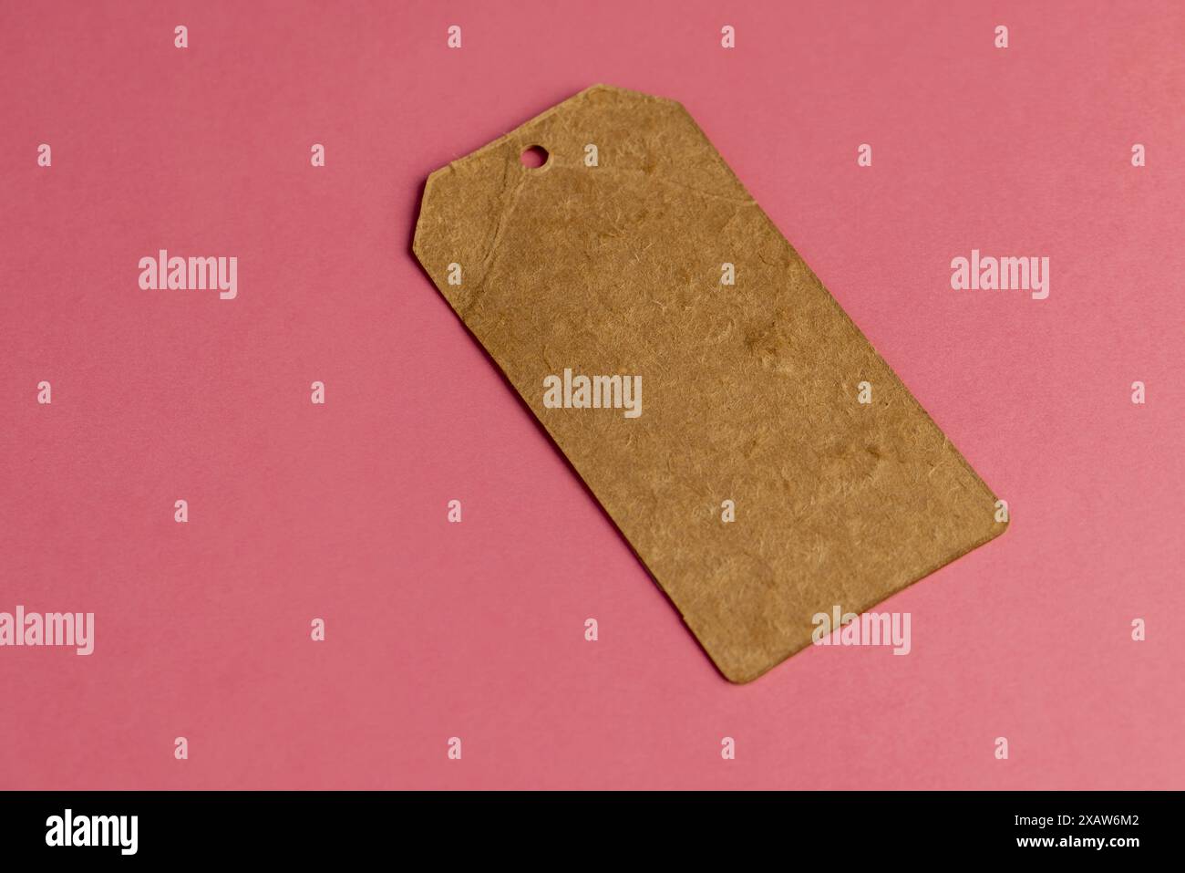 ancienne étiquette de vêtements en carton fabriquée à partir de vieux papiers recyclés étiquette d'article écologique sur fond rose Banque D'Images