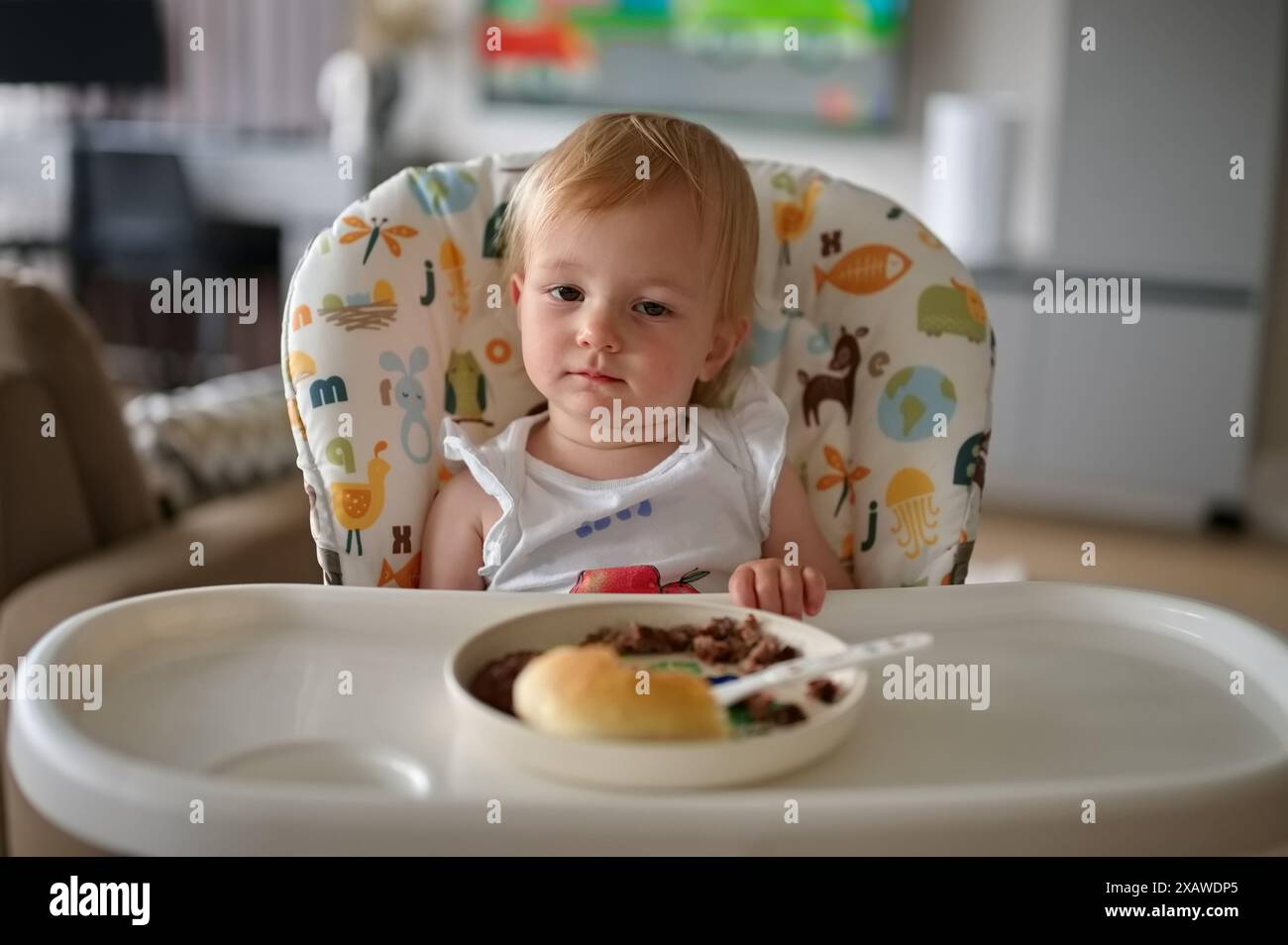 Adorable petite fille assise dans une chaise haute et mangeant Banque D'Images