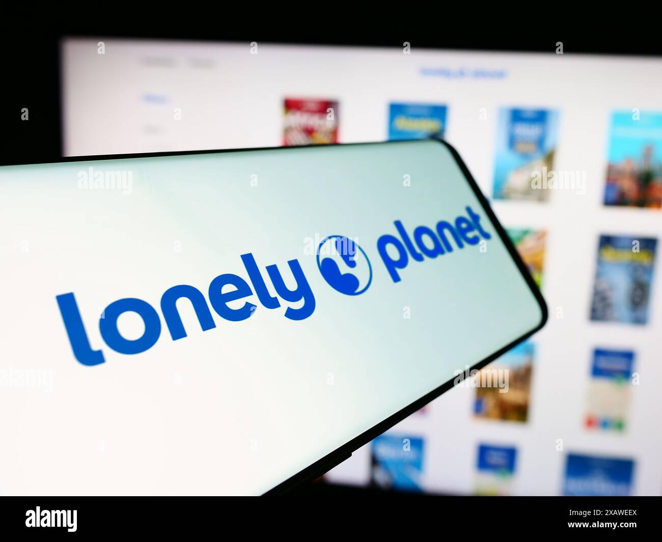 Téléphone portable avec logo de la compagnie de guide de voyage Lonely Planet devant le site Web de l'entreprise. Mettez l'accent sur le centre-gauche de l'écran du téléphone. Banque D'Images