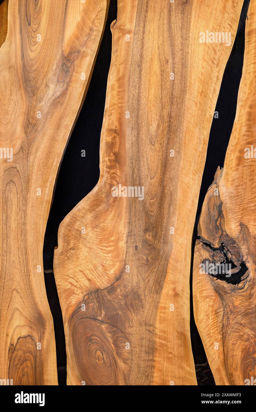 Un beau motif de grain de bois sous la forme d'un plateau de table en bois lisse avec des guides verticaux remplis de résine époxy noire. Banque D'Images