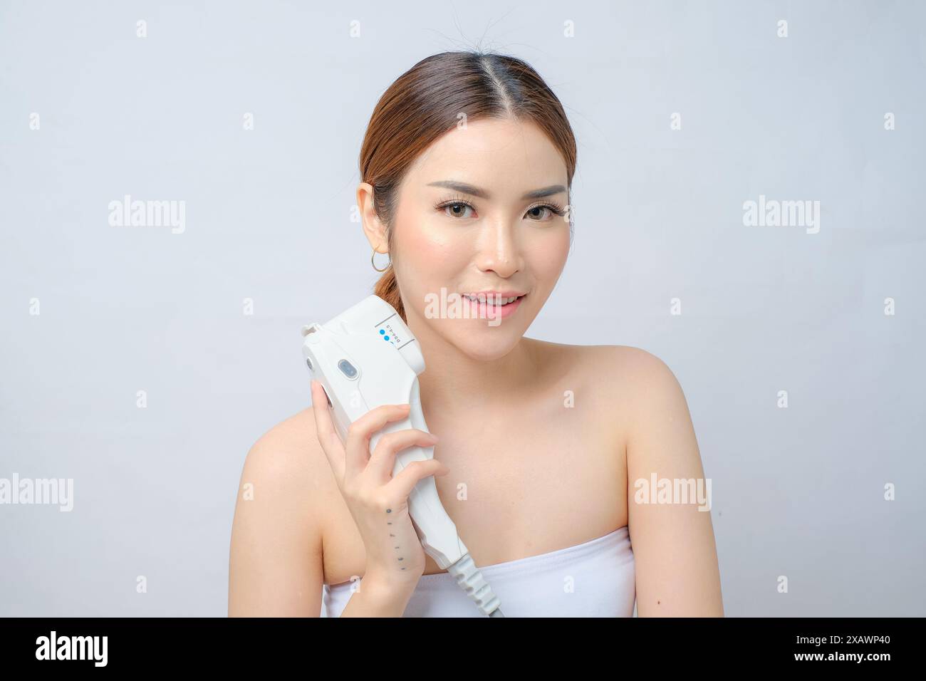 Jeune femme asiatique appréciant la procédure faciale laser HIFU au centre de beauté fond blanc isolé Banque D'Images