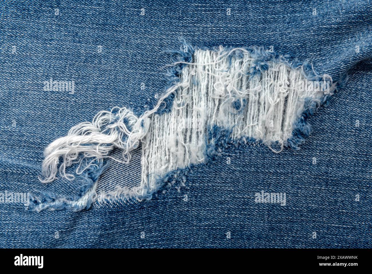 Trou dans le jeans gros plan. Texture de denim délavé Banque D'Images