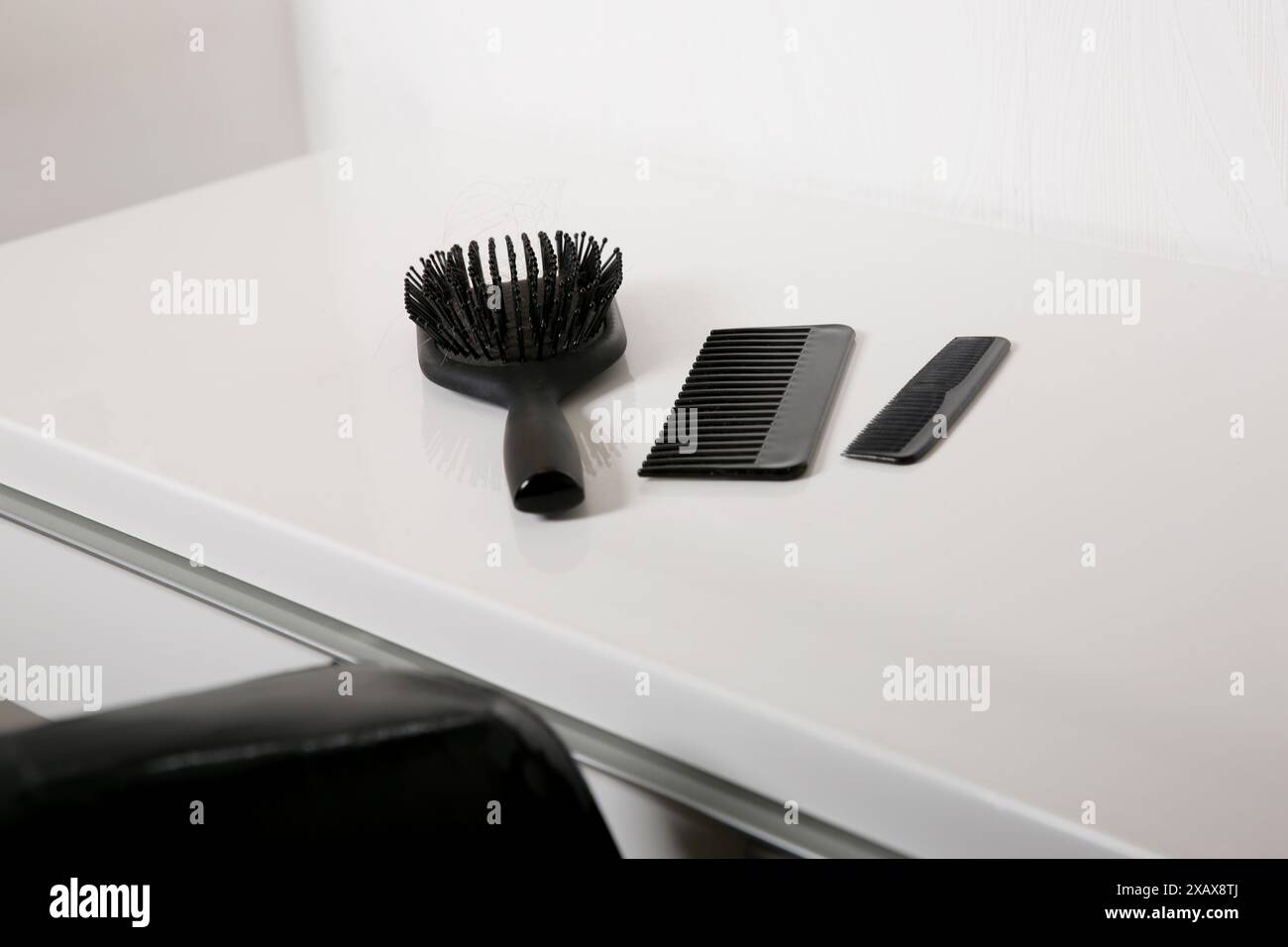 Brosse à cheveux et peignes utilisés avec quelques cheveux sur la table blanche, hygiène de la peau de la tête Banque D'Images