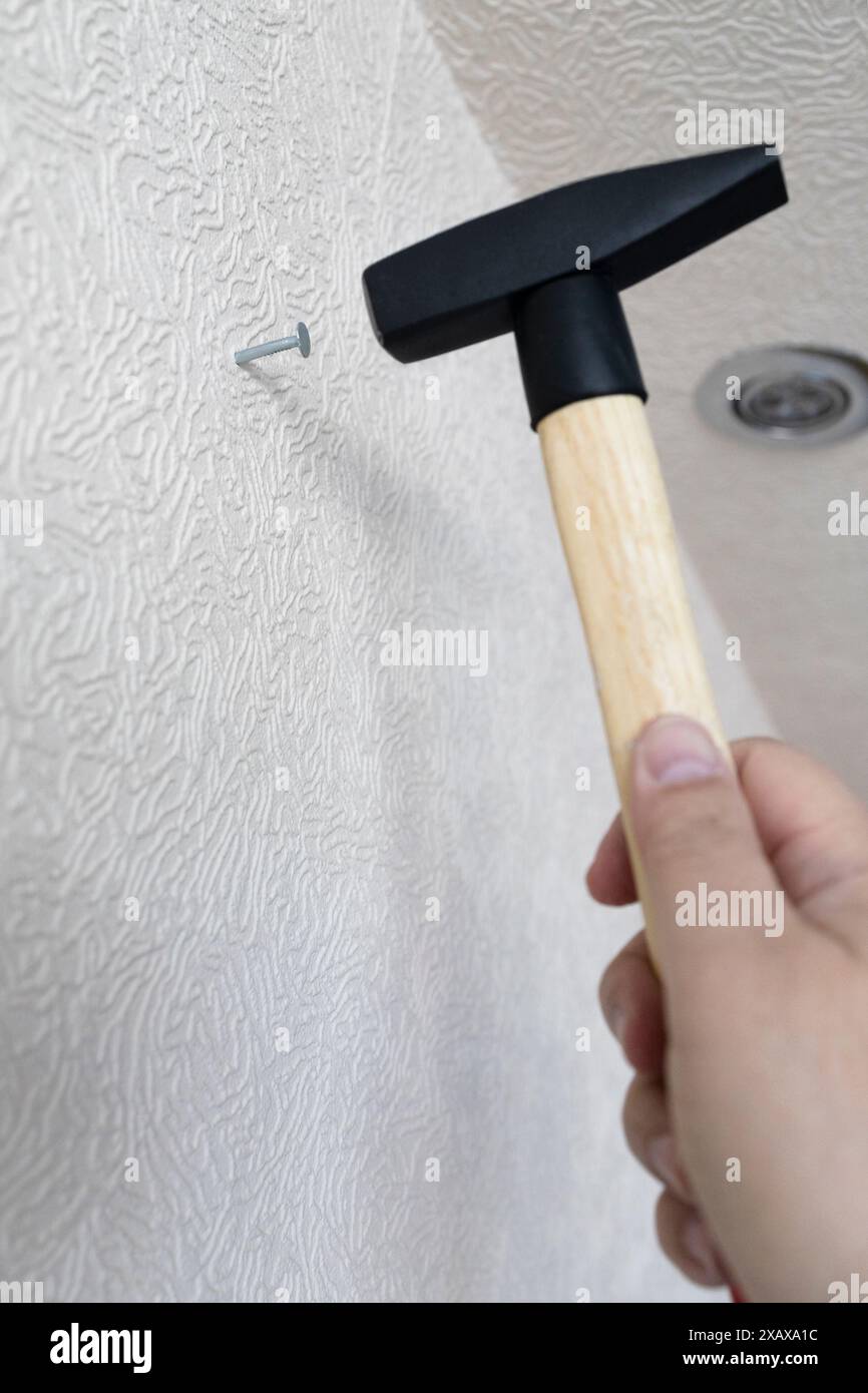 main masculine avec des marteaux de marteau clou dans le mur dans la maison Banque D'Images