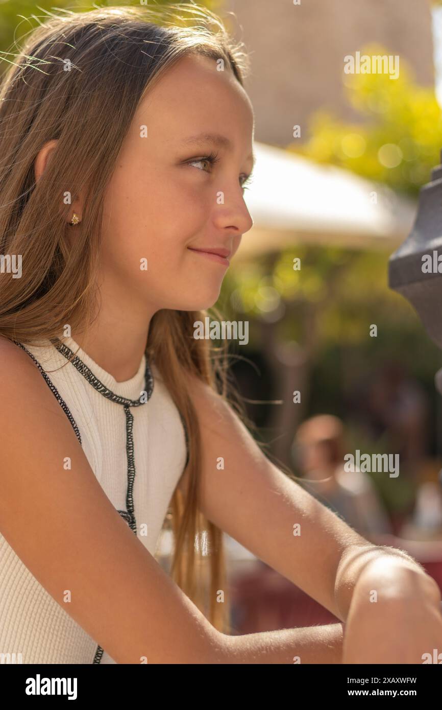 Cette photographie montre une belle fille aux longs cheveux blonds et aux yeux verts éclatants, posant pour un portrait. Banque D'Images