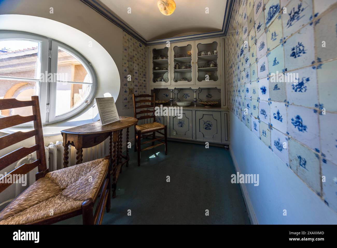 Dans la petite cuisine de la maison de Carl et Olga Milles à Millesgården sur l'île de Lidingö près de Stockholm, bordée de carreaux de Delft bleu et blanc, les deux artistes prenaient ensemble leur premier café chaque matin. Une fenêtre ovale, une vitrine en porcelaine avec des pièces de porcelaine et deux chaises à dossier en escalier avec des sièges en jonc définissent la pièce. Carl Milles (1875–1955) et son épouse autrichienne, la peintre Olga Milles, ont acheté la propriété en 1906 et y ont vécu jusqu'en 1931. Depuis 1936, Millesgården est une fondation, offerte en cadeau au peuple suédois. Bodal, Lidingö kommun, comté de Stockholm, Suède. Banque D'Images