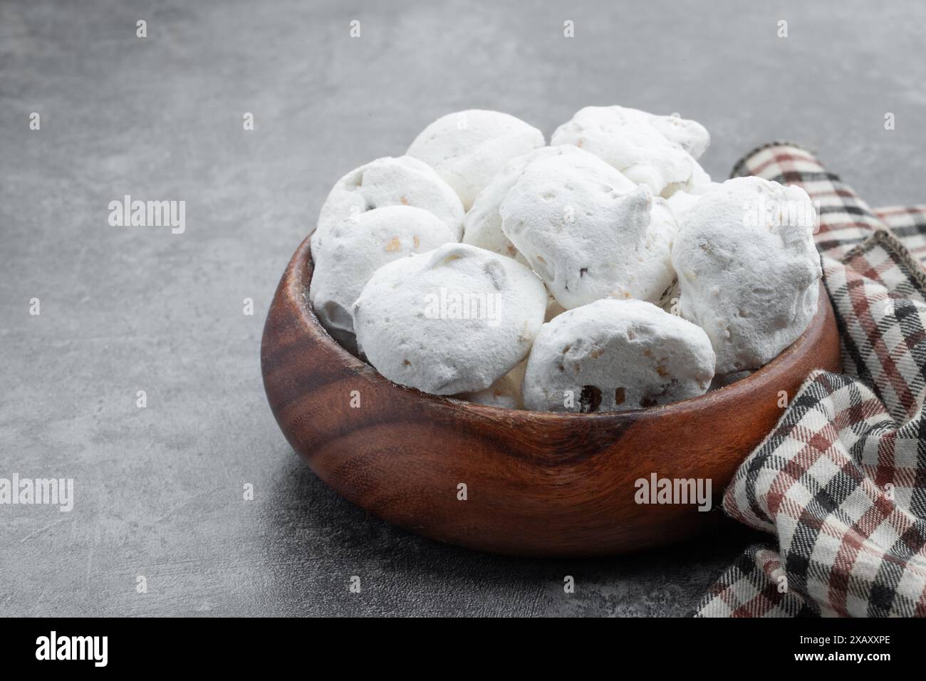 Mini meringues traditionnelles avec des noix dans un bol en bois sur fond gris Banque D'Images