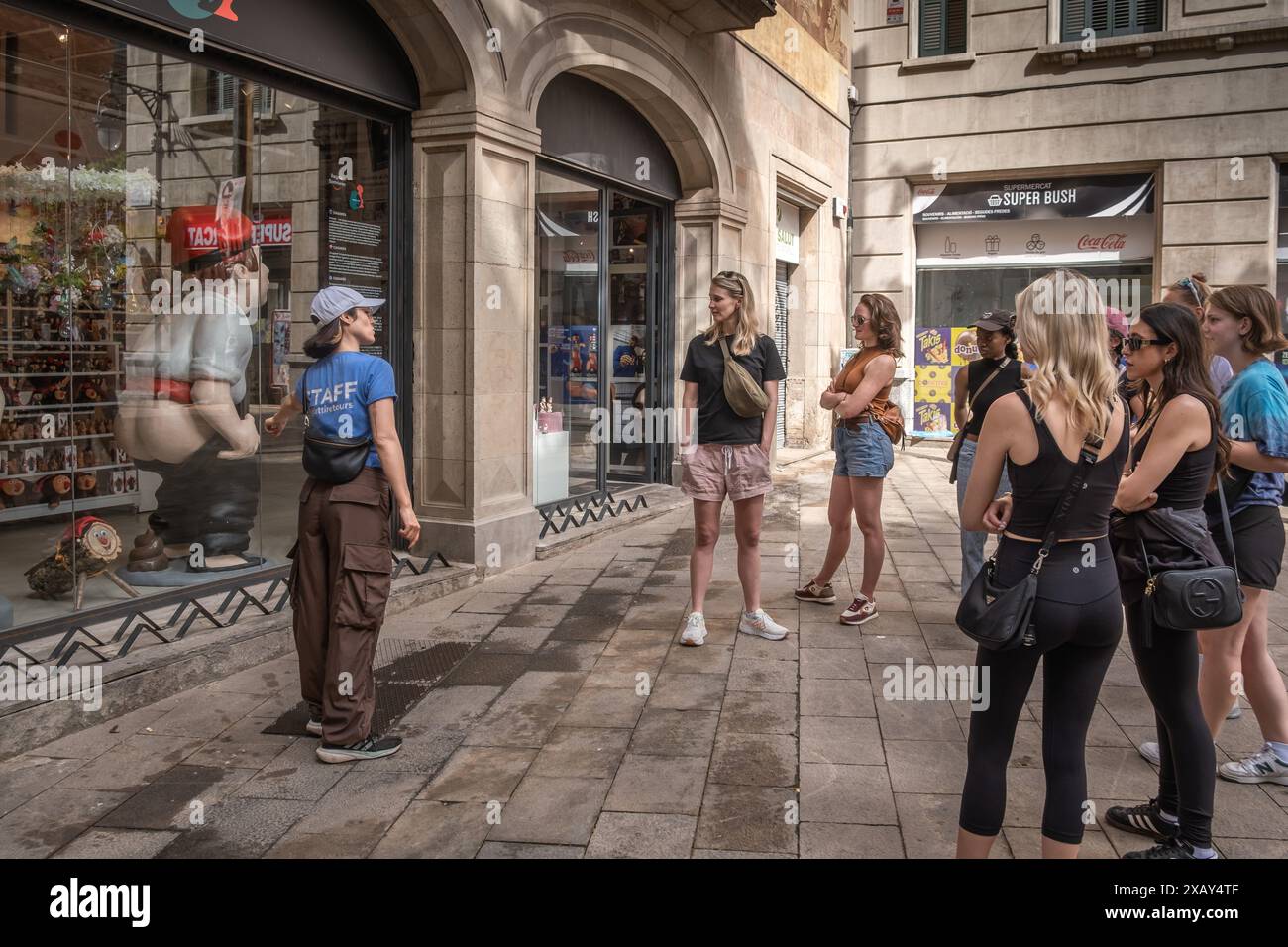 Un groupe de touristes participe à l'activité d'un guide touristique qui leur montre un grand berger 'caganer' défécant utilisé dans la crèche traditionnelle catalane de Noël. Comme la plupart des capitales européennes, Barcelone vit entre la nécessité d'une économie touristique dont elle ne peut se passer et le rejet d'un grand nombre de citoyens contre la distorsion culturelle et la précarité de l'emploi typiques de l'industrie touristique. Les slogans sur les espaces publics de la dernière manifestation contre la surpopulation touristique coexistent avec une activité touristique qui ne se repose jamais. Banque D'Images