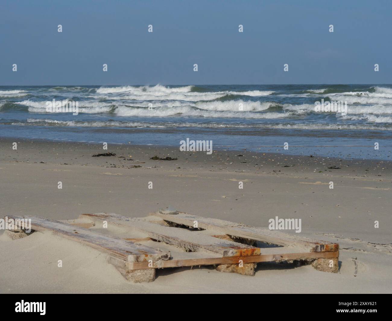 Planches en bois dans le sable sur la plage avec mer ondulée et ciel clair, juist, frise orientale, allemagne Banque D'Images