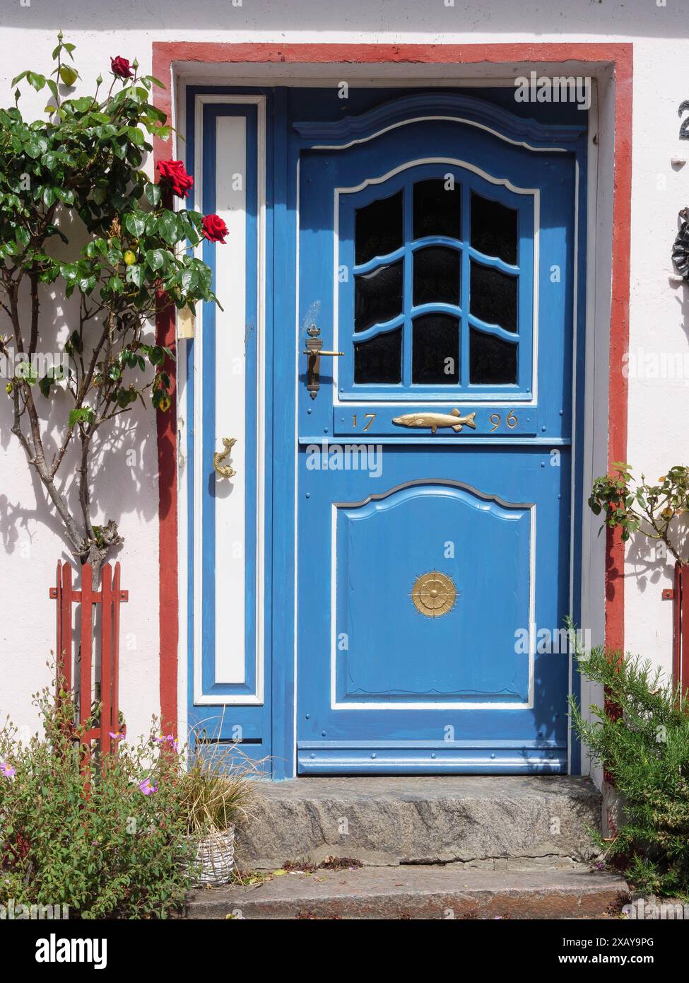 Porte d'entrée décorée bleue d'une maison, entourée de fleurs en fleurs et d'éléments décoratifs, Schleswig, Schleswig-Holstein, Allemagne Banque D'Images