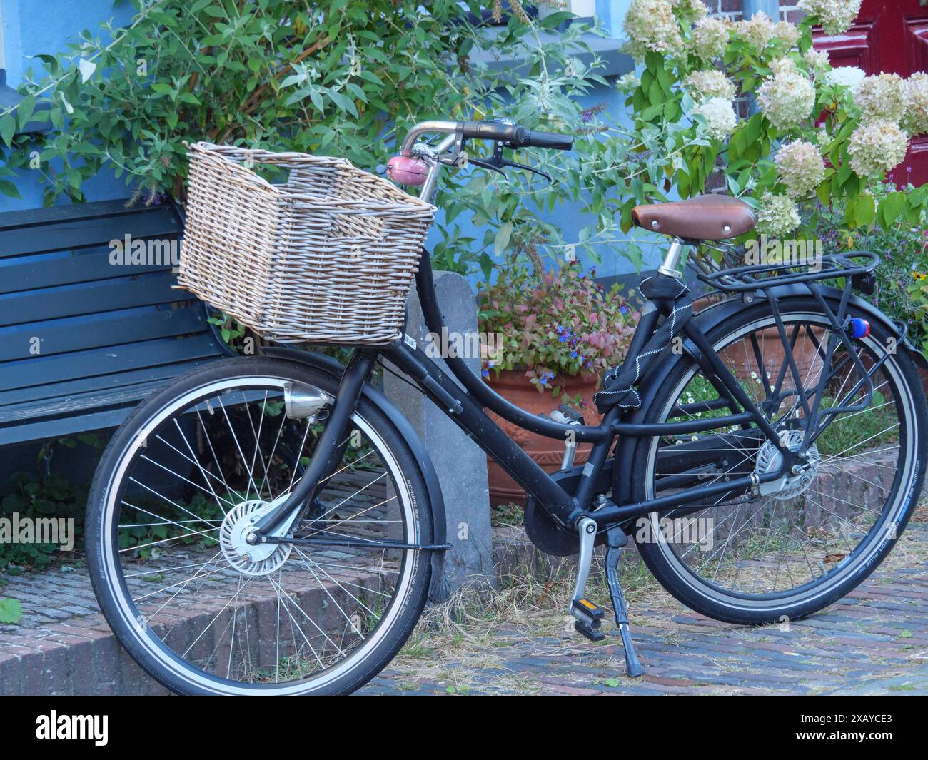 Un vélo avec un panier se tient à côté d'un banc, entouré de plantes, Doesburg, pays-Bas Banque D'Images