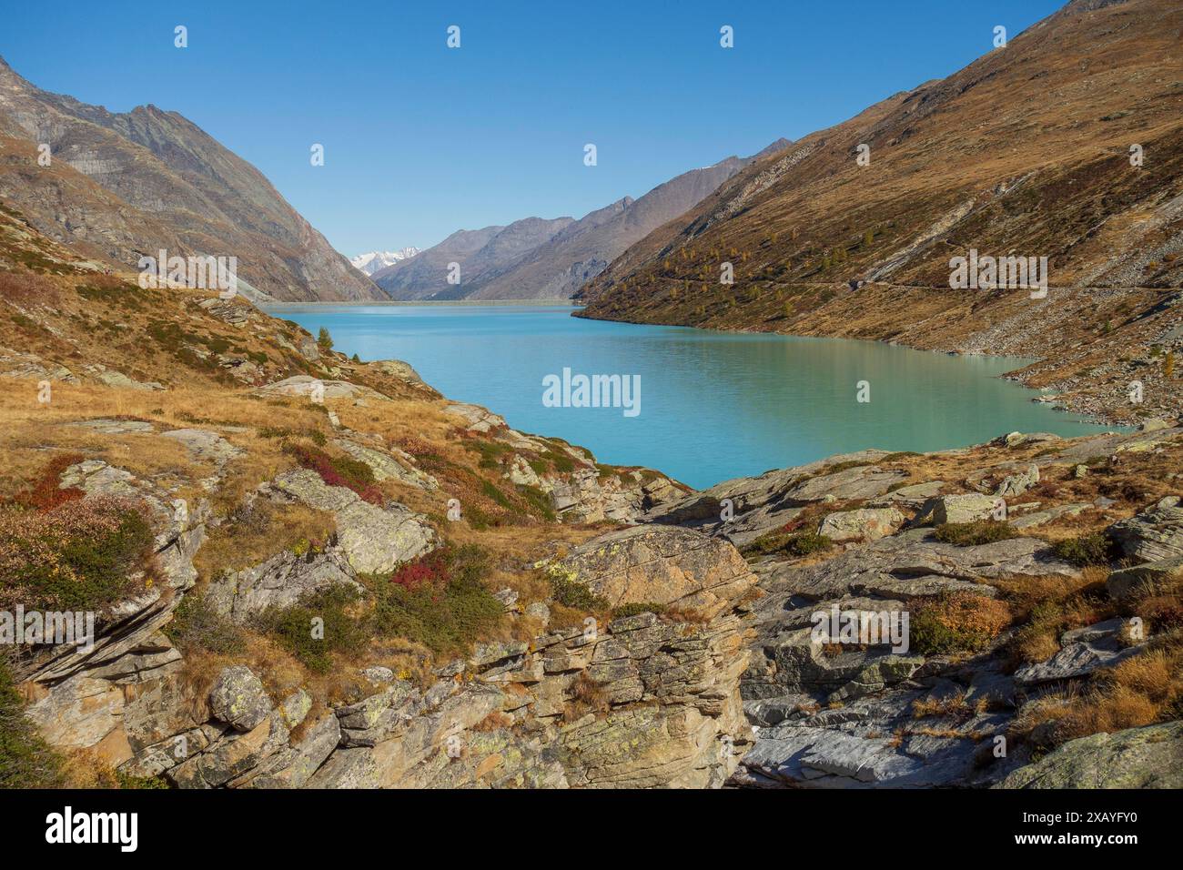 Un lac clair, vert-bleu se trouve dans une vallée, entouré de paysages de montagnes rocheuses sous un ciel bleu, saas Fee, suisse Banque D'Images