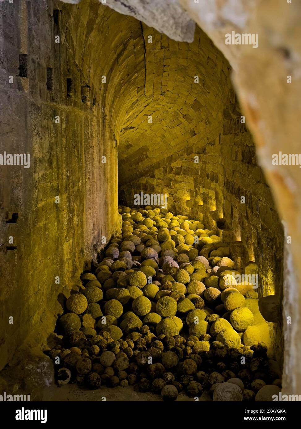 Couloir voûté historique aujourd'hui illuminé de lumière jaune à l'intérieur de vieilles balles de pierre pierres boulets de canon munitions historiques dans la forteresse construite Banque D'Images