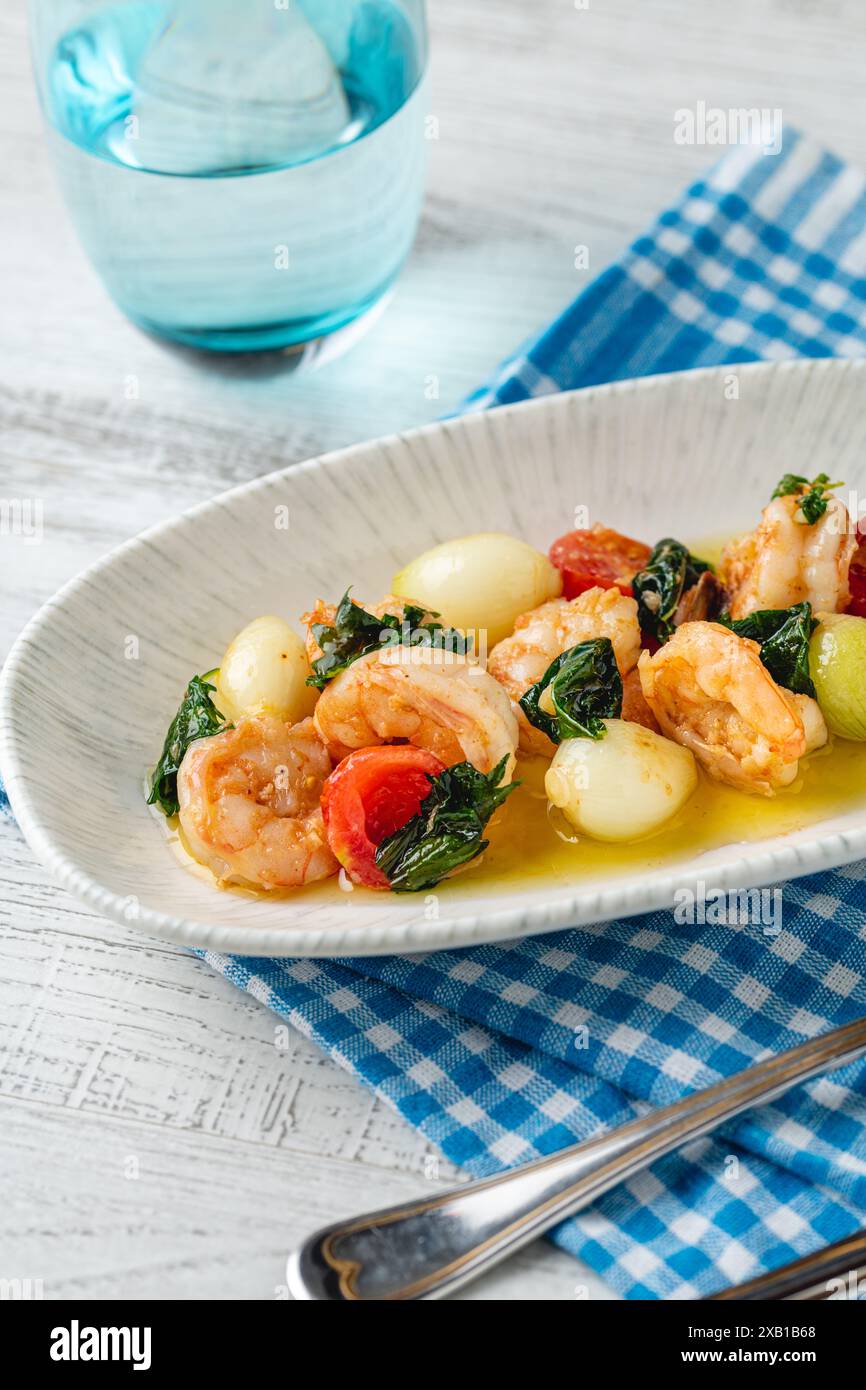 Apéritif avec des crevettes, des oignons et des tomates sur une assiette en porcelaine blanche Banque D'Images