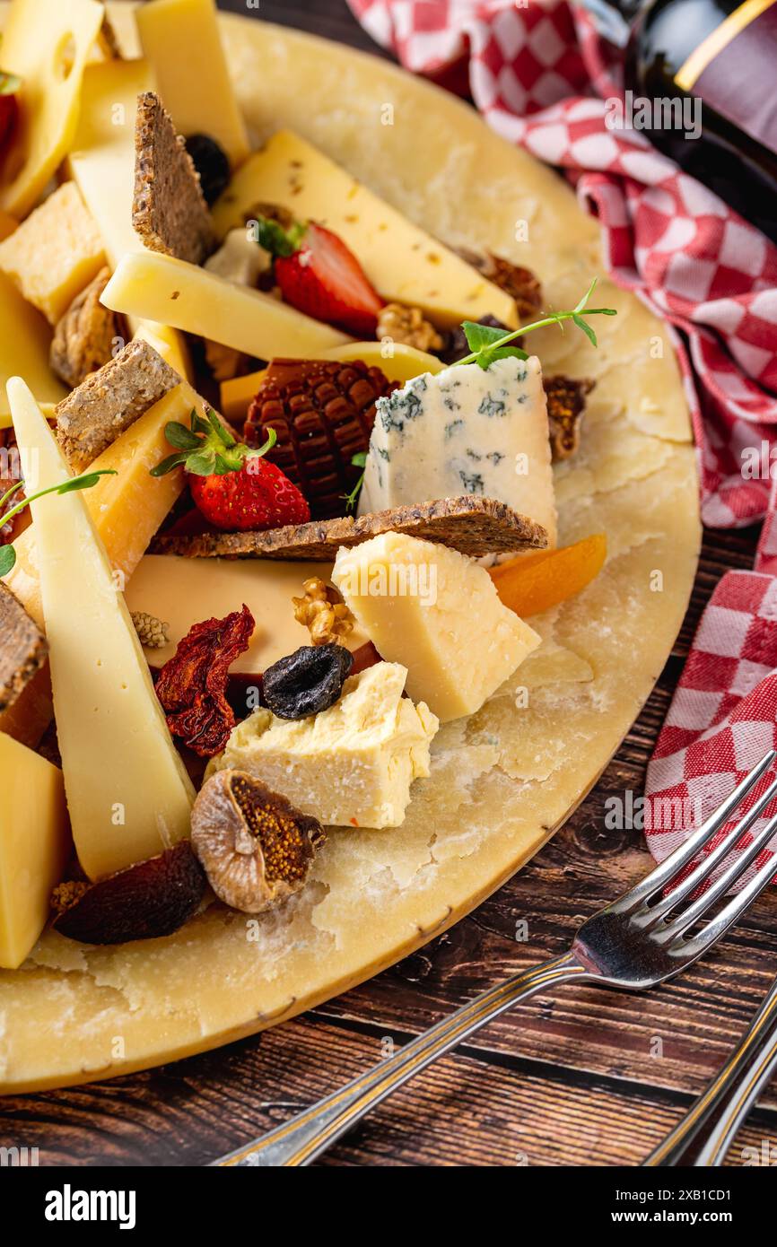 Assiette de fromage préparée avec des fromages de luxe et du vin sur une table en bois Banque D'Images