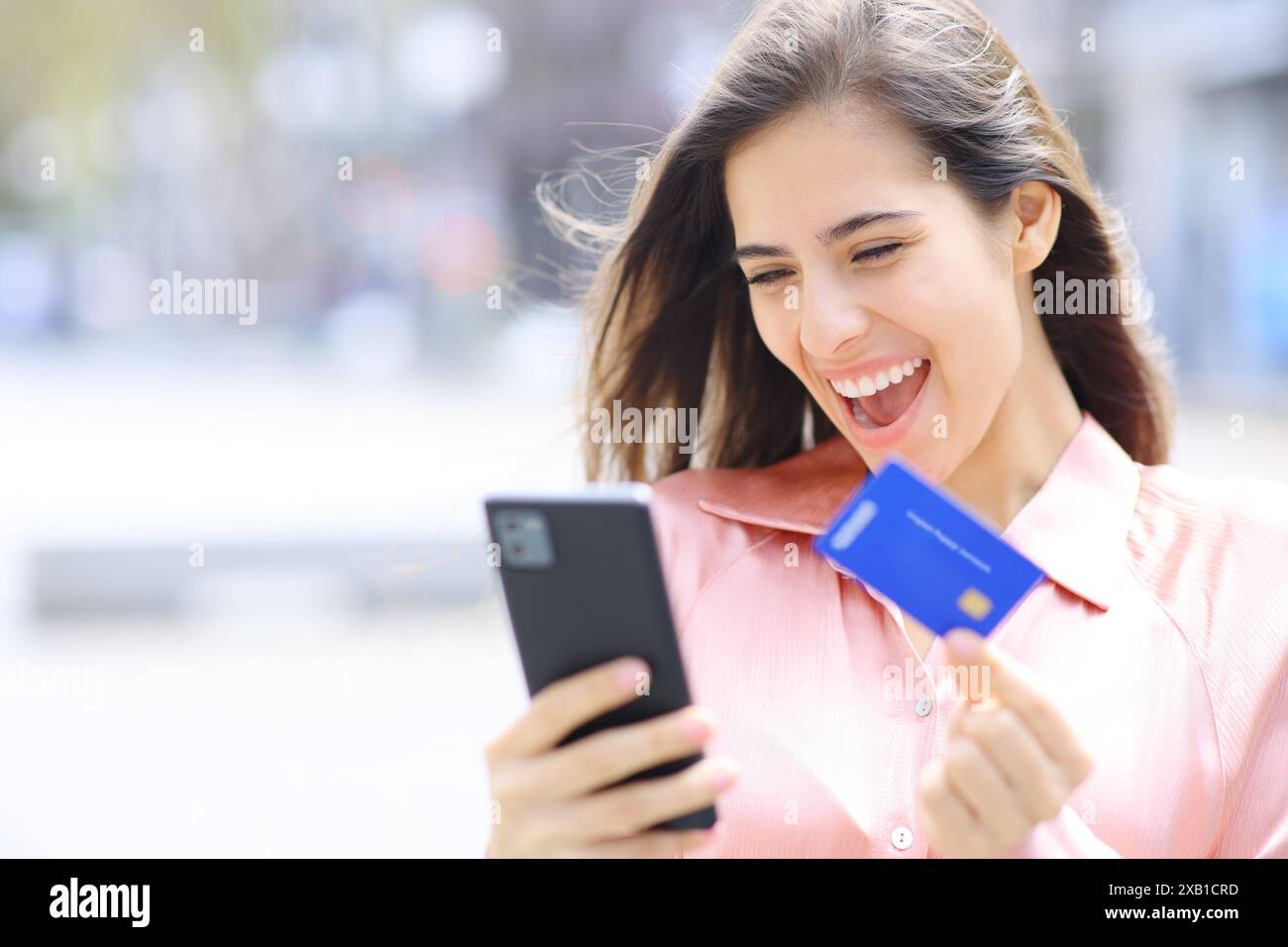Femme élégante excitée achetant en ligne avec téléphone et carte de crédit Banque D'Images