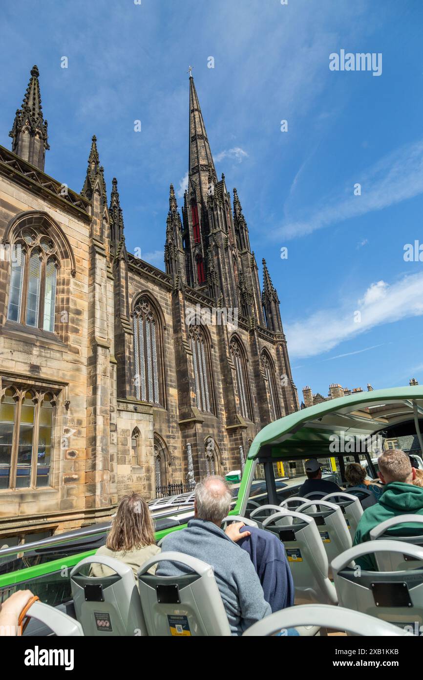 Un groupe de touristes assis sur un bus à toit ouvert passant devant le Tolbooth Kirk sur le Royal Mile, Édimbourg Banque D'Images