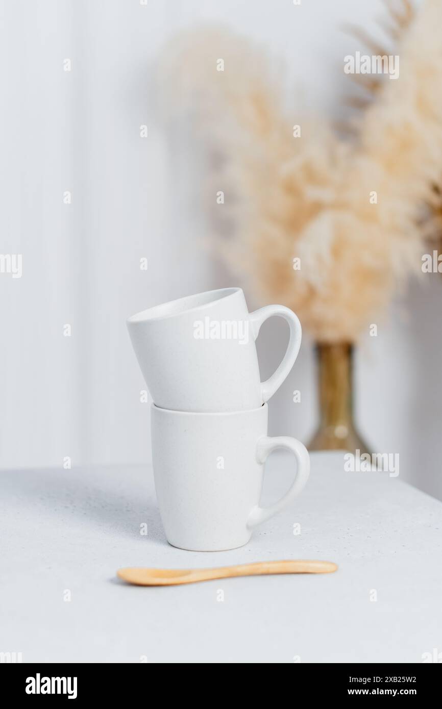 Gros plan de tasses à café blanches sur table dans une cuisine lumineuse Banque D'Images Gros plan de tasses à café blanches sur table dans une cuisine lumineuse Banque D'Images