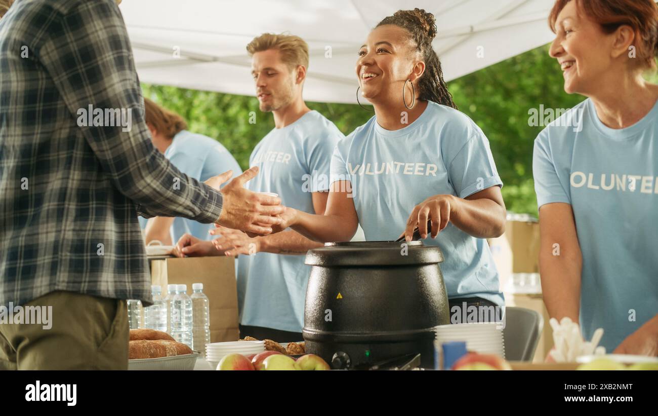 Groupe positif de jeunes volontaires adultes servant de la nourriture gratuite pour les pauvres dans le besoin. Les travailleurs caritatifs aident les membres de la communauté. Aide humanitaire aux réfugiés et aux immigrants. Banque D'Images