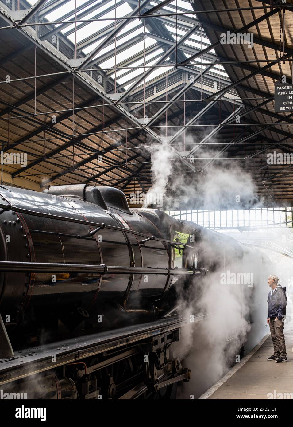 Homme debout sur le quai un de la gare de Pickering regardant à travers la vapeur. North Yorkshire, Angleterre, Royaume-Uni. Photographie couleur. Banque D'Images