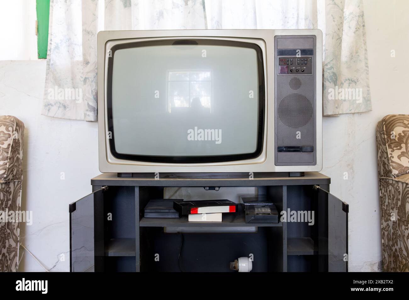 Un téléviseur à l'ancienne avec cadrans et haut-parleur sur un stand, mettant en valeur une ambiance de salon d'antan. Banque D'Images