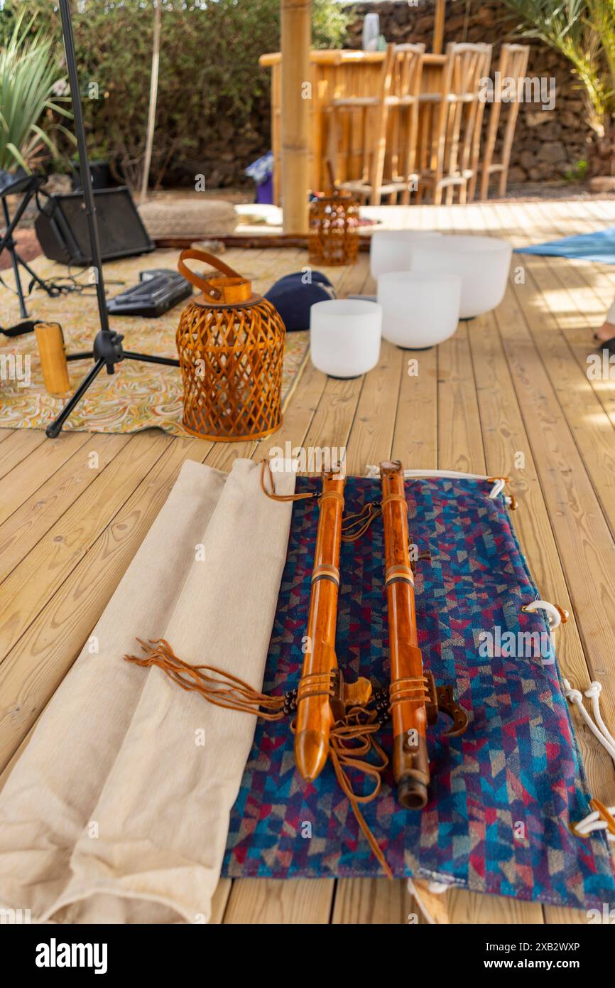 Un cadre extérieur préparé pour une séance de sonothérapie, avec une sélection de bols tibétains, de bols en cristal et d'instruments à vent traditionnels, posés Banque D'Images