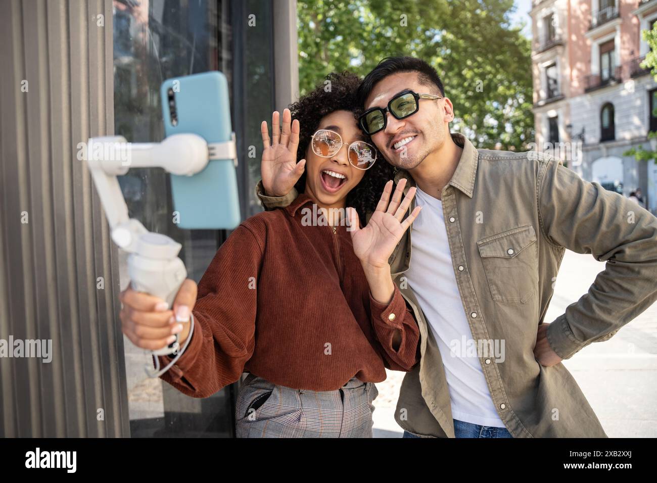Un joyeux couple multiethnique, un Chinois et une femme hispanique, prennent un selfie avec un téléphone sur un cardan à Madrid, en Espagne. Ils font signe et sourient à la Banque D'Images
