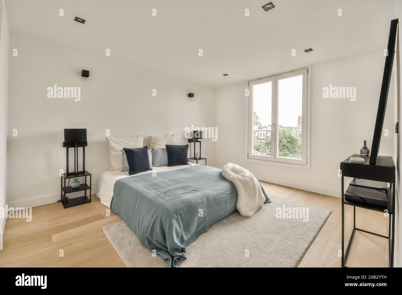 Chambre moderne aux tons neutres, lumière naturelle et une touche de bleu pour une sensation de sérénité. Idéal pour les thèmes de design d'intérieur contemporain. Banque D'Images