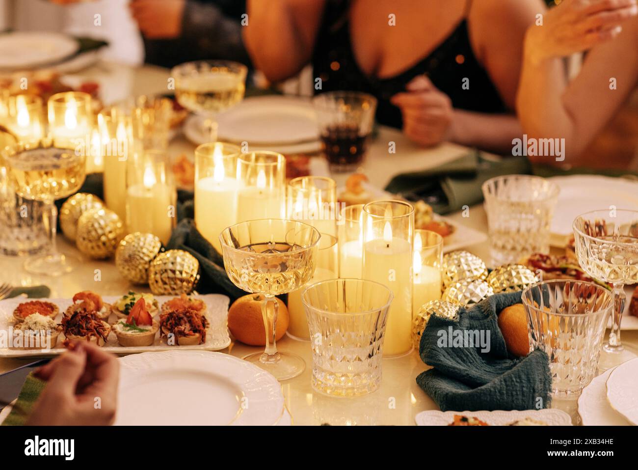 Une table de fête couverte avec décor du nouvel an. Bougies allumées, collations, boules de Noël, assiettes et verres sur la nappe. Une fête de Noël. Un fest Banque D'Images