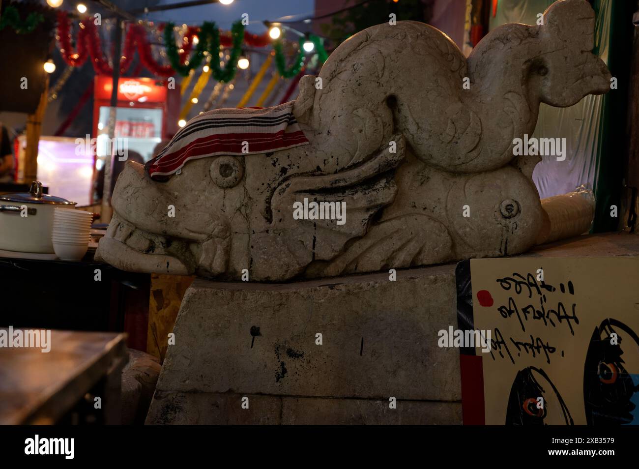 Dans les rues d'alfama pendant les festivités populaires des saints, une sculpture en pierre d'une créature mythique ressemblant à un poisson est ornée d'un chiffon de séchage Banque D'Images