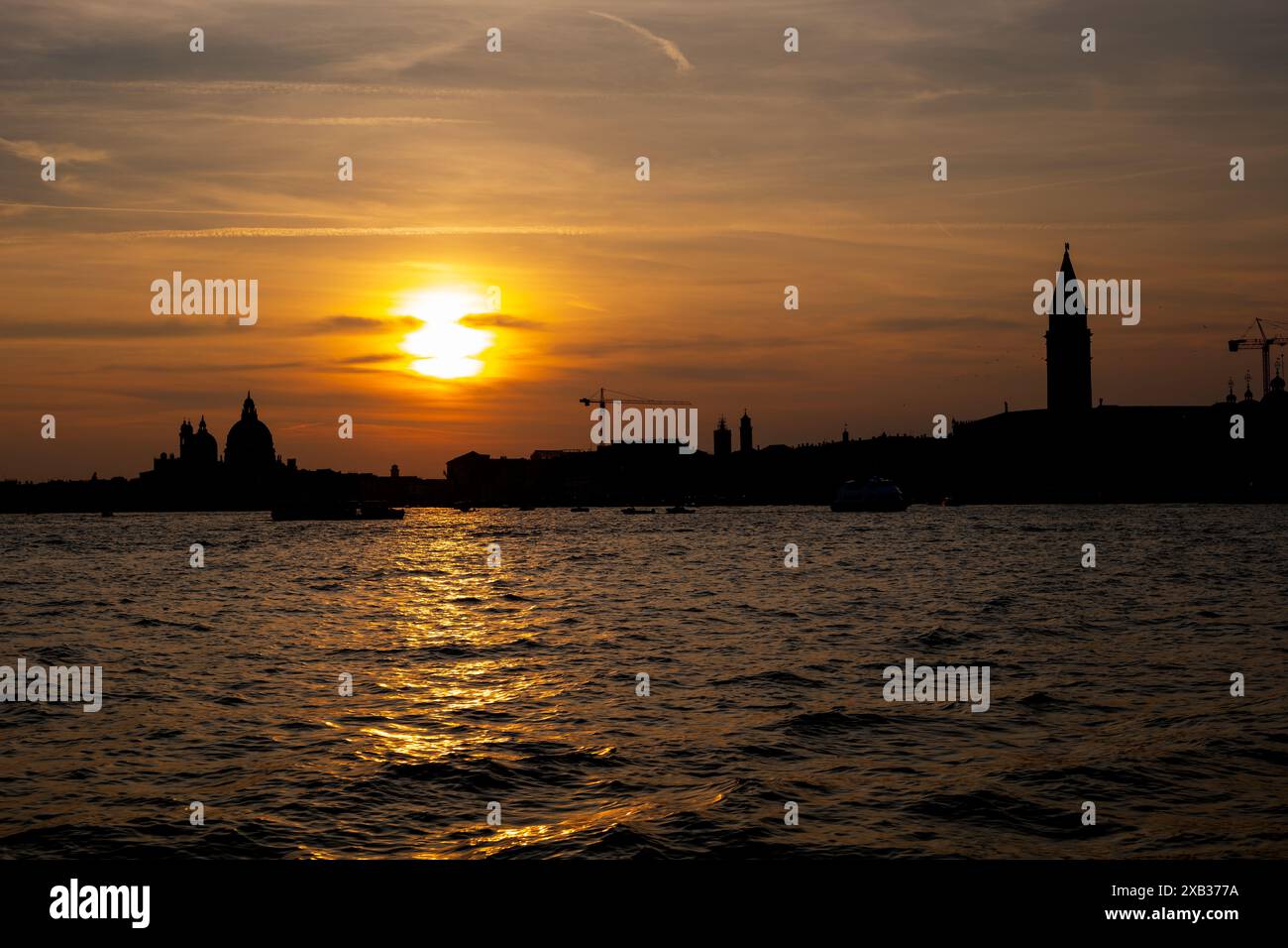 Silhouette de la ville de Venise au coucher du soleil depuis la lagune vénitienne en Italie. Banque D'Images