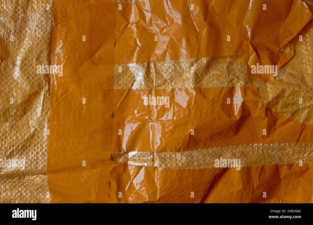 Sac tissé en plastique orange avec des bandes de fond grunge de ruban adhésif. Fragment de sac d'expédition. Texture de sac pp tissé utilisée. Banque D'Images