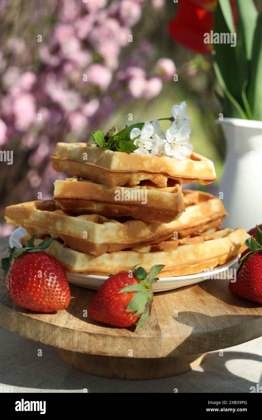Gaufres fraîchement cuites et beau bouquet de tulipes sur table dans le jardin, gros plan Banque D'Images