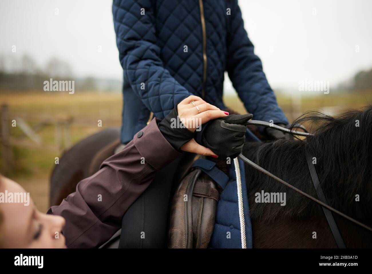 Section médiane de la fille assise sur le cheval par instructeur féminin Banque D'Images