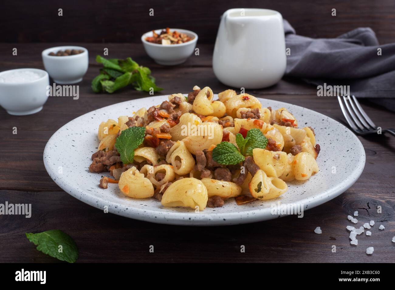 Pâtes cuites avec du bœuf haché et des légumes, macaronis de style marine sur une assiette. Fond en bois foncé Banque D'Images
