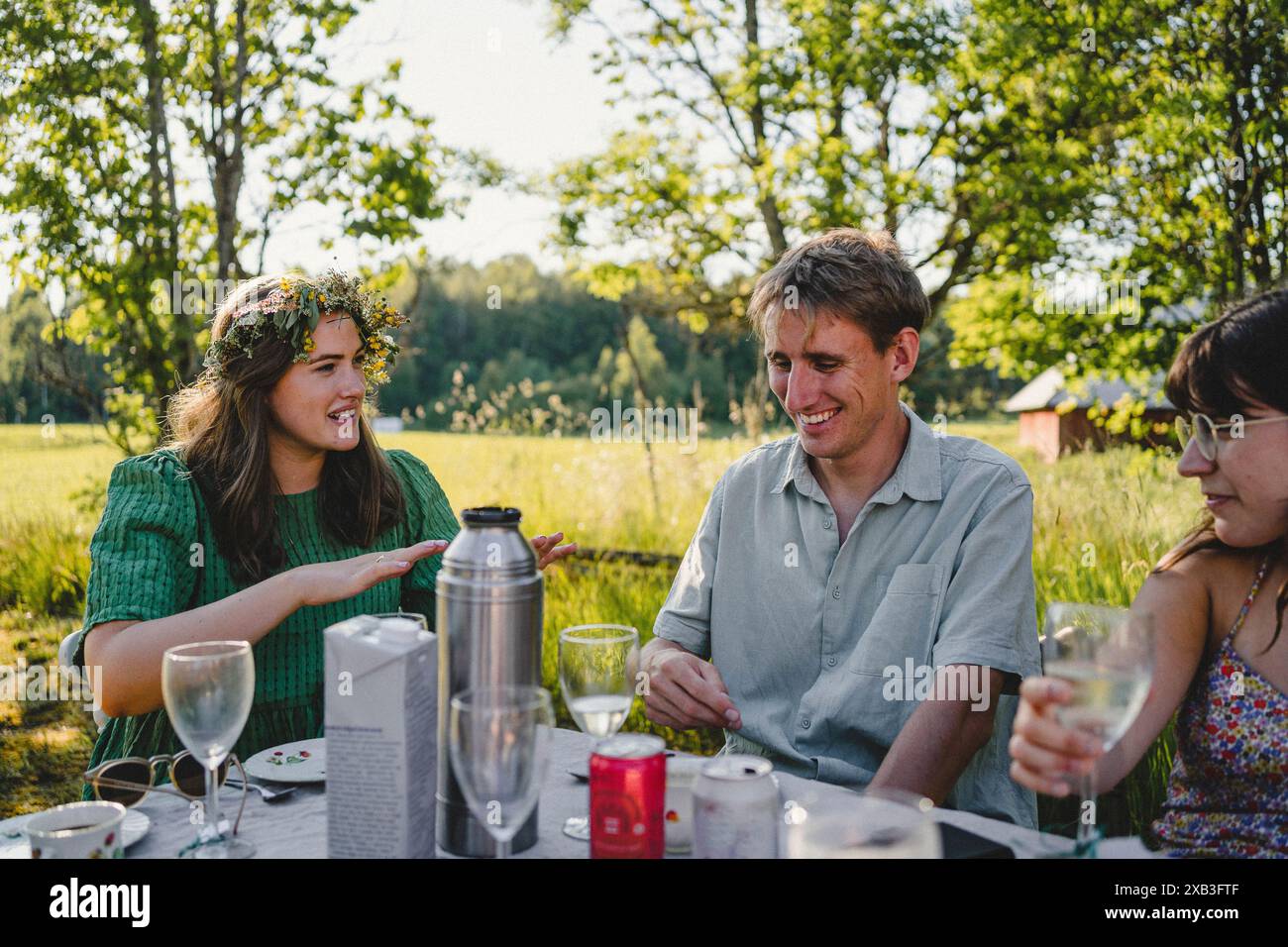 Heureux jeune homme assis parmi des amies féminines tout en profitant du solstice d'été à l'arrière cour pendant le brunch Banque D'Images