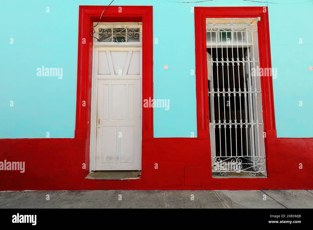 380 façade vert menthe et rouge de la maison coloniale dans la zone du centre historique montrant la fenêtre fréquente de grille à volets en bois, en forme de porte. Bayamo-Cuba. Banque D'Images
