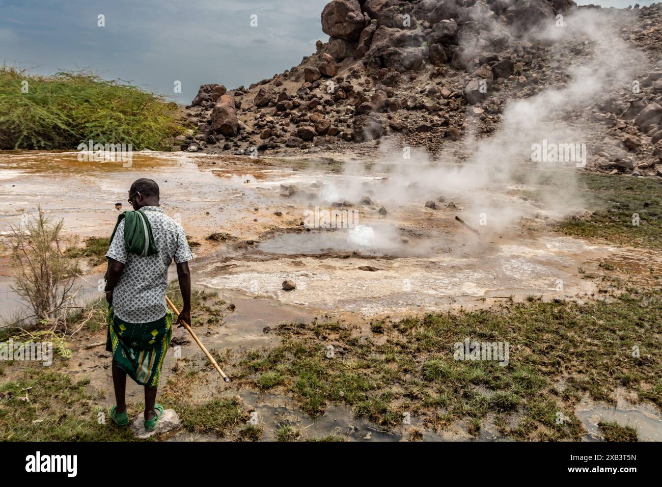 Guide local traditionnellement habillé montrant des sources naturelles volcaniques géothermiques chaudes avec piscine vapeur et petits lacs colorés, geysers et criques Banque D'Images