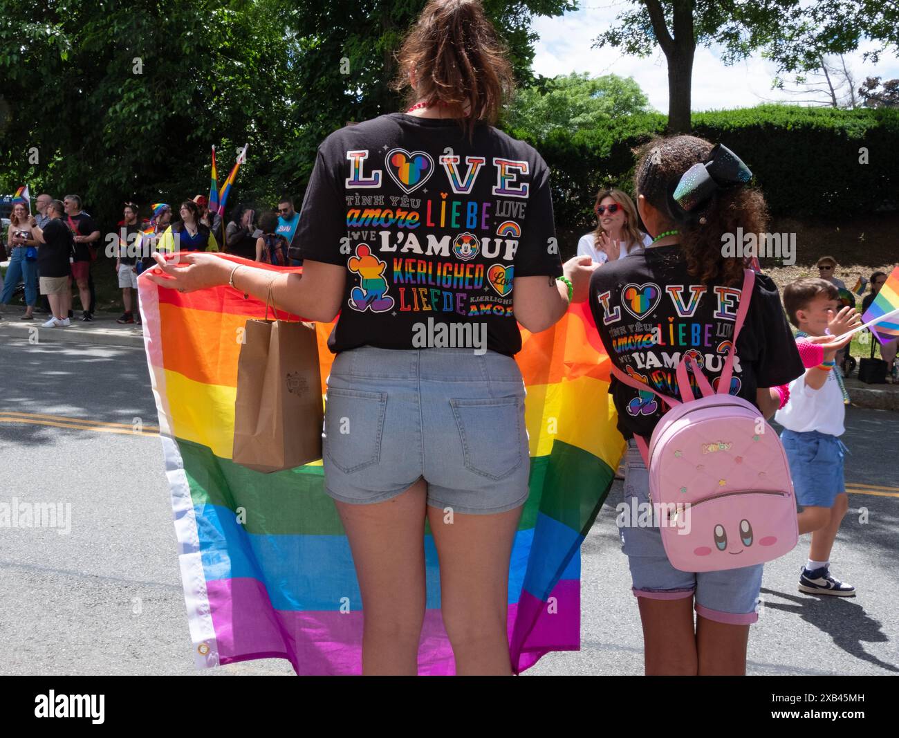 Vue arrière d'une mère et sa fille portant un t-shirt assorti avec le mot amour en plusieurs langues. Sur la route du défilé de 2024 Poughkeepsie Pride. Banque D'Images
