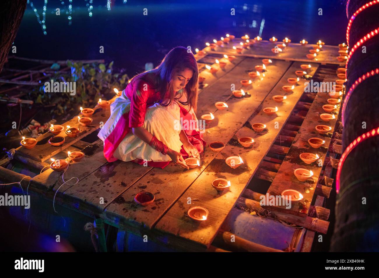 Une jeune femme illumine des lampes Diwali dans l'étang du temple Sri Sri Baradeswari Kalimata à Basabo à Dhaka, au Bangladesh. Banque D'Images