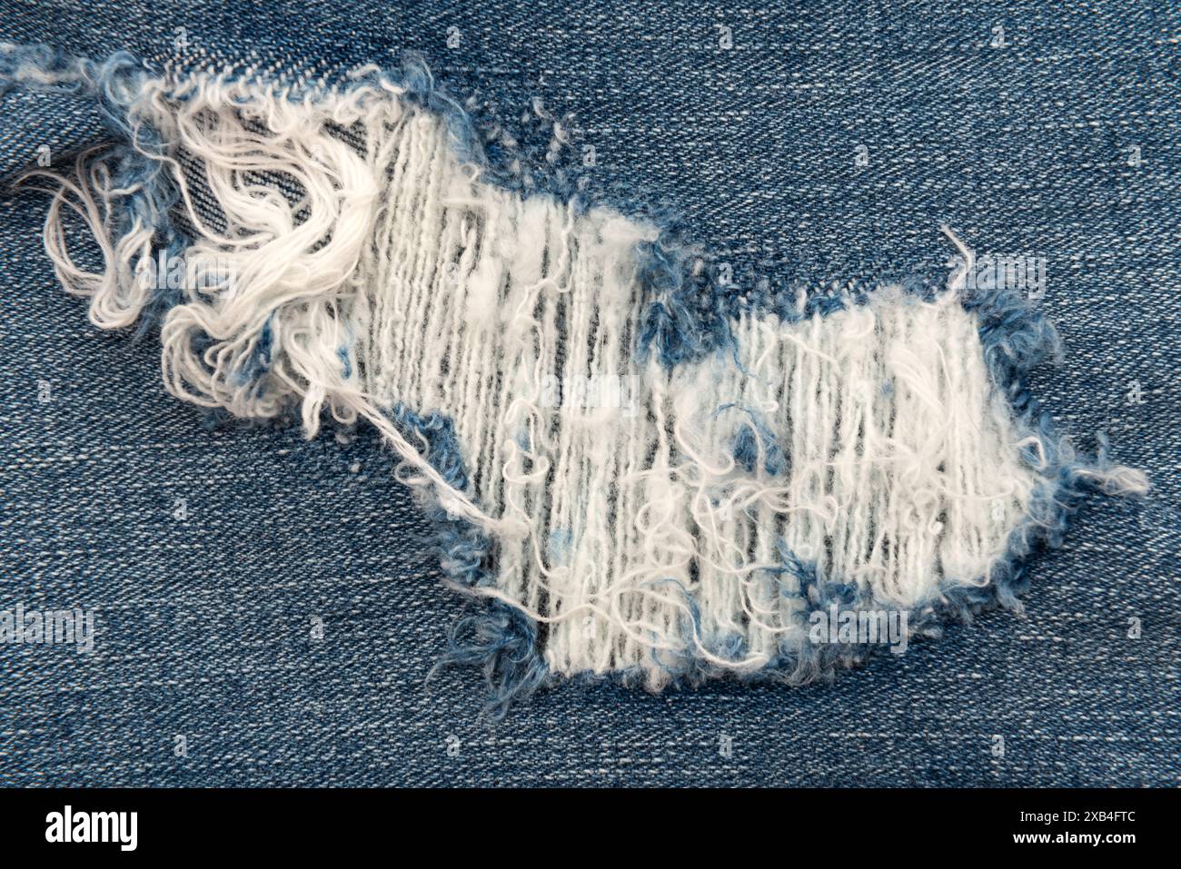 Trou dans le jeans gros plan. Texture de denim délavé Banque D'Images