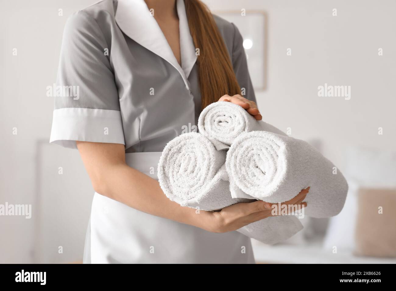 Femme de chambre avec des serviettes roulées dans la chambre d'hôtel, gros plan Banque D'Images