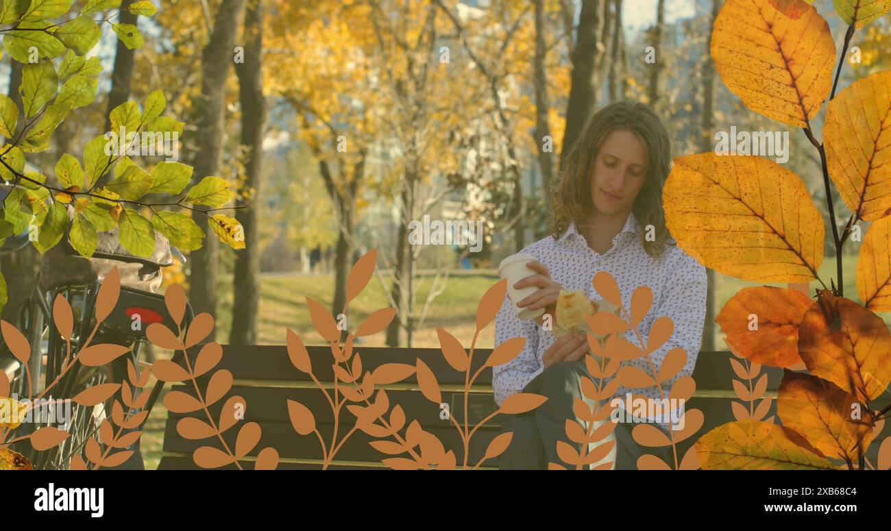Jeune homme caucasien assis sur le banc tenant une tasse de café dans le parc Banque D'Images