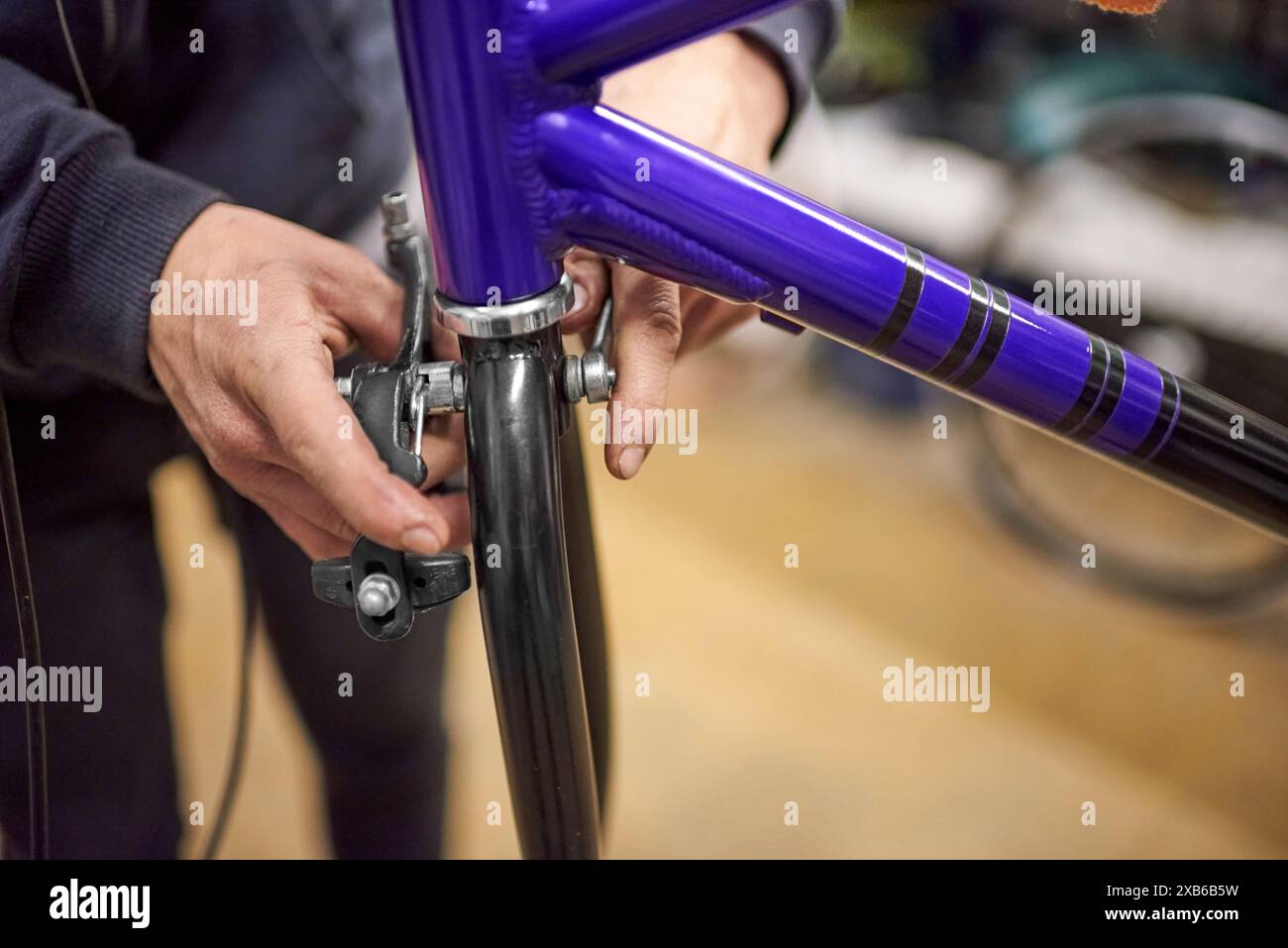 Homme inconnu assemblant le système de freinage d'une bicyclette dans le cadre du service d'entretien qu'il effectue dans son atelier. De vraies personnes au travail. Banque D'Images